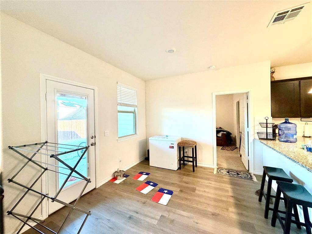 Wood-finish flooring throughout, bright recessed lighting, and a white paneled door with glass insert