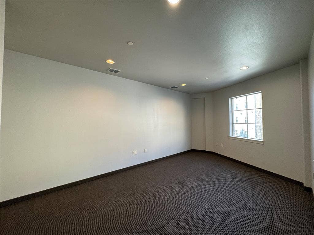 Recessed lighting, window with grid pattern, neutral wall paint, dark patterned carpeting, and white trim