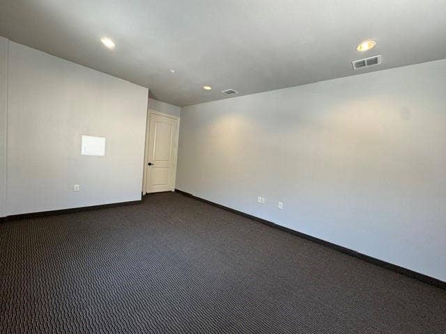 Light gray painted walls, recessed lighting, and patterned dark gray carpeting