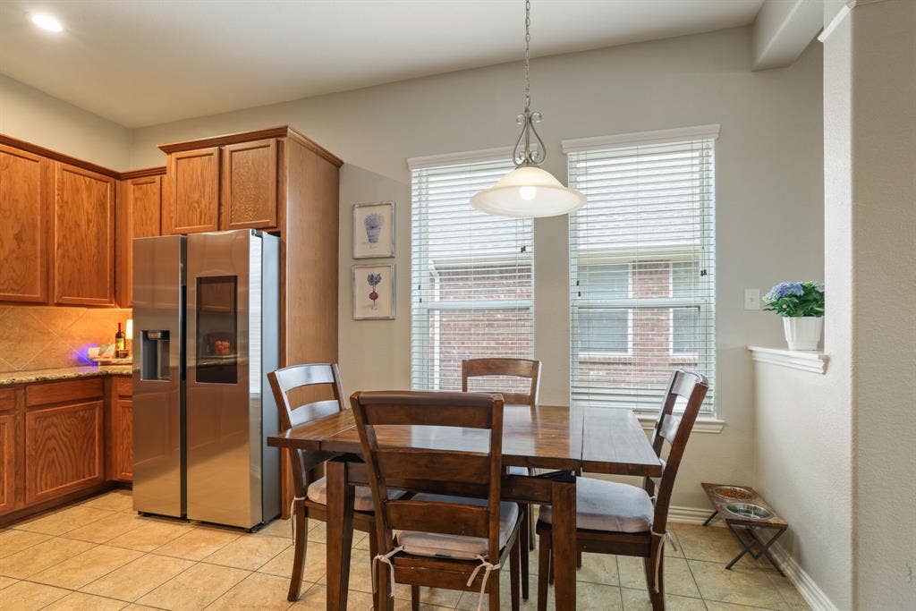 1213 Egret Court, Little Elm, TX 75068 Kitchen featuring wood cabinetry, stainless steel refrigerator, tile flooring, and a dining area with pendant lighting