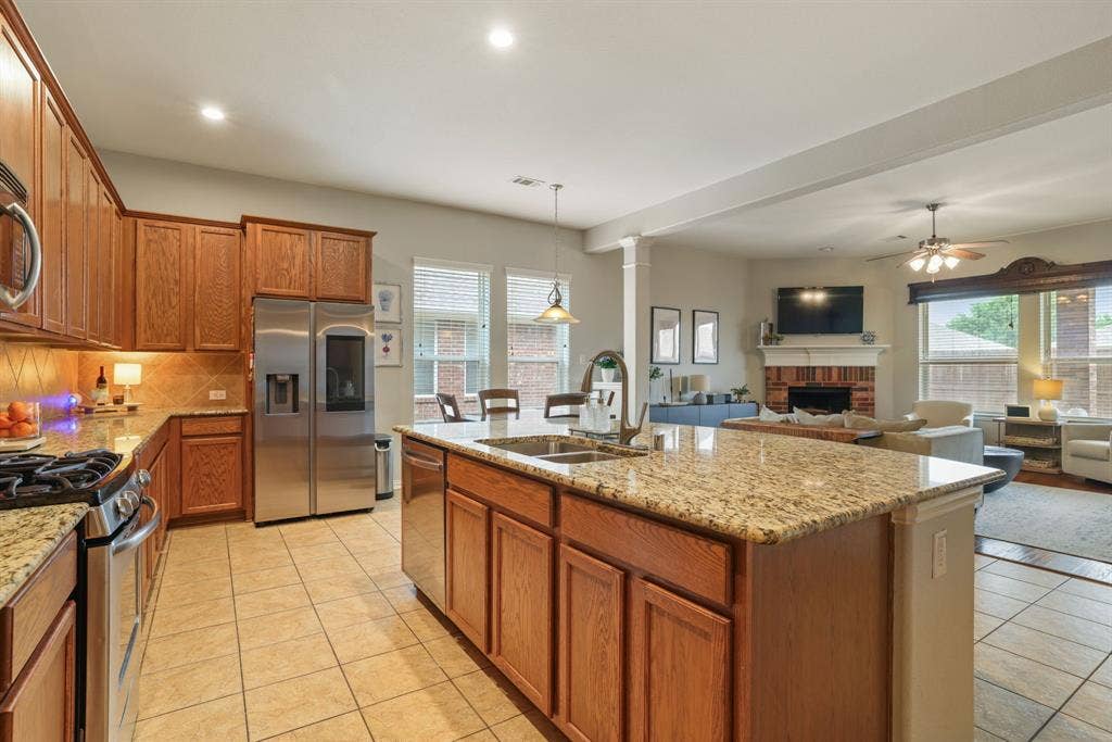 1213 Egret Court, Little Elm, TX 75068 Kitchen featuring wood cabinetry, granite countertops, tile flooring, and stainless steel appliances