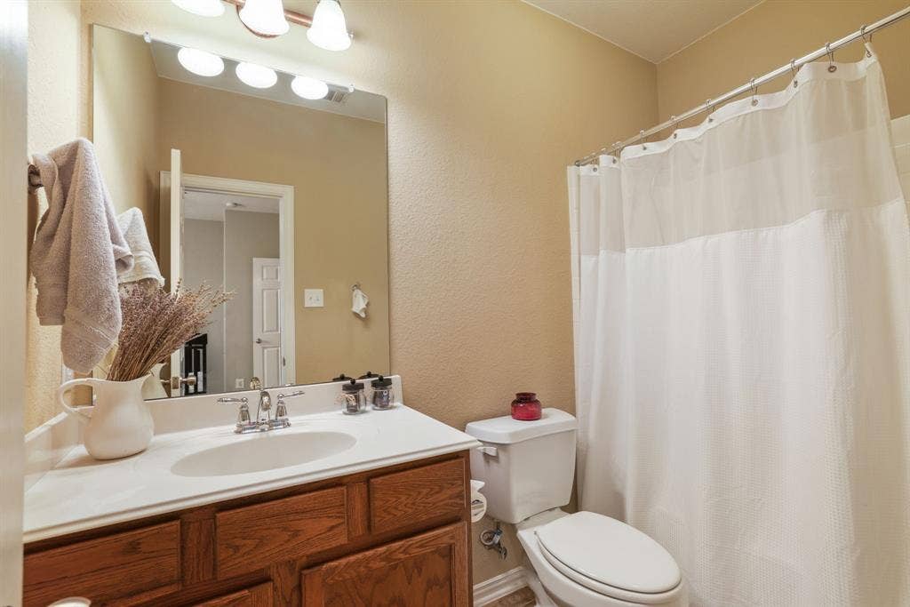 1213 Egret Court, Little Elm, TX 75068 Bathroom featuring a vanity with wood-finish cabinetry, a white countertop, and a shower-tub combination