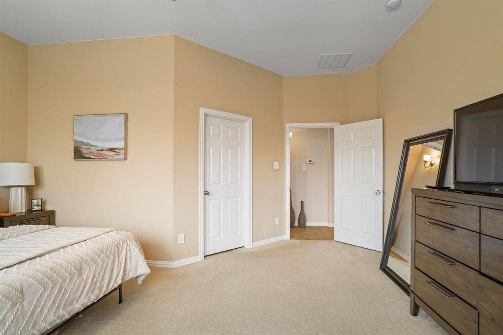 1213 Egret Court, Little Elm, TX 75068 Light beige carpeting, warm neutral wall paint, two white paneled doors, and a ceiling-mounted light fixture