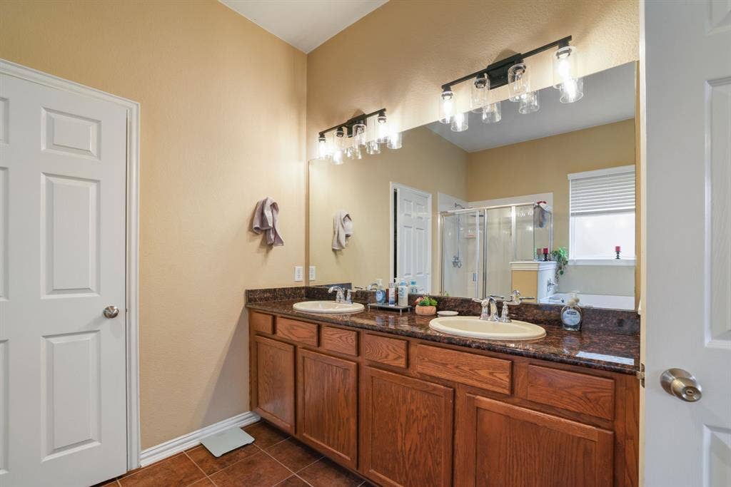 1213 Egret Court, Little Elm, TX 75068 Double vanity with undermount sinks, stone-look countertop, and wood-finish cabinetry