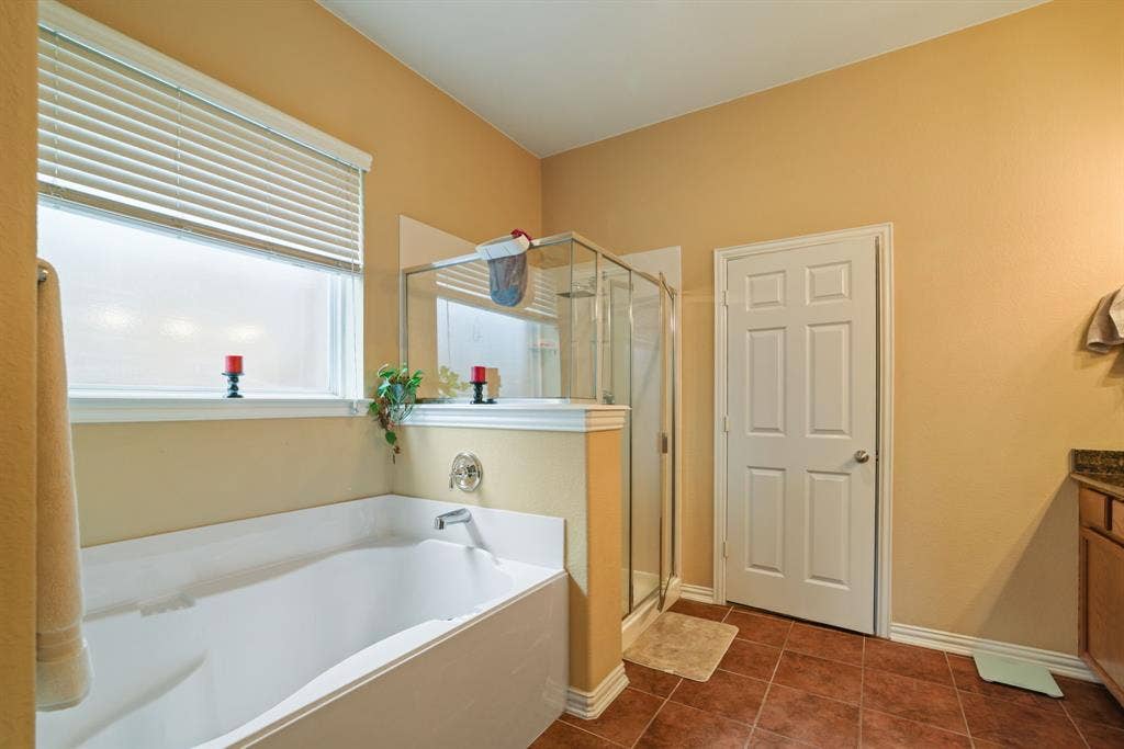 1213 Egret Court, Little Elm, TX 75068 Soaking tub, enclosed glass shower, window with blinds, tile flooring, and a vanity with a stone countertop