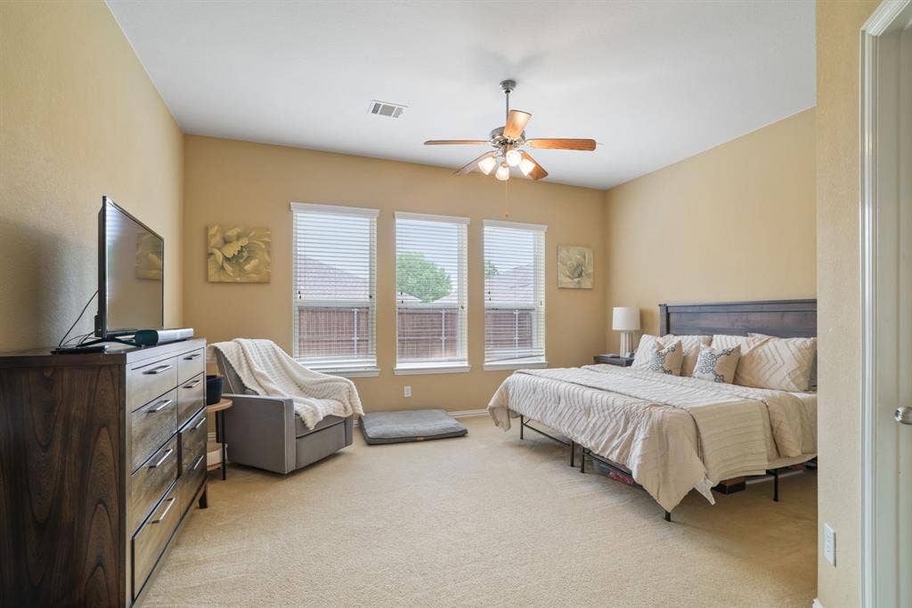 1213 Egret Court, Little Elm, TX 75068 Vaulted ceiling with a ceiling fan, three windows with blinds, and carpeted flooring