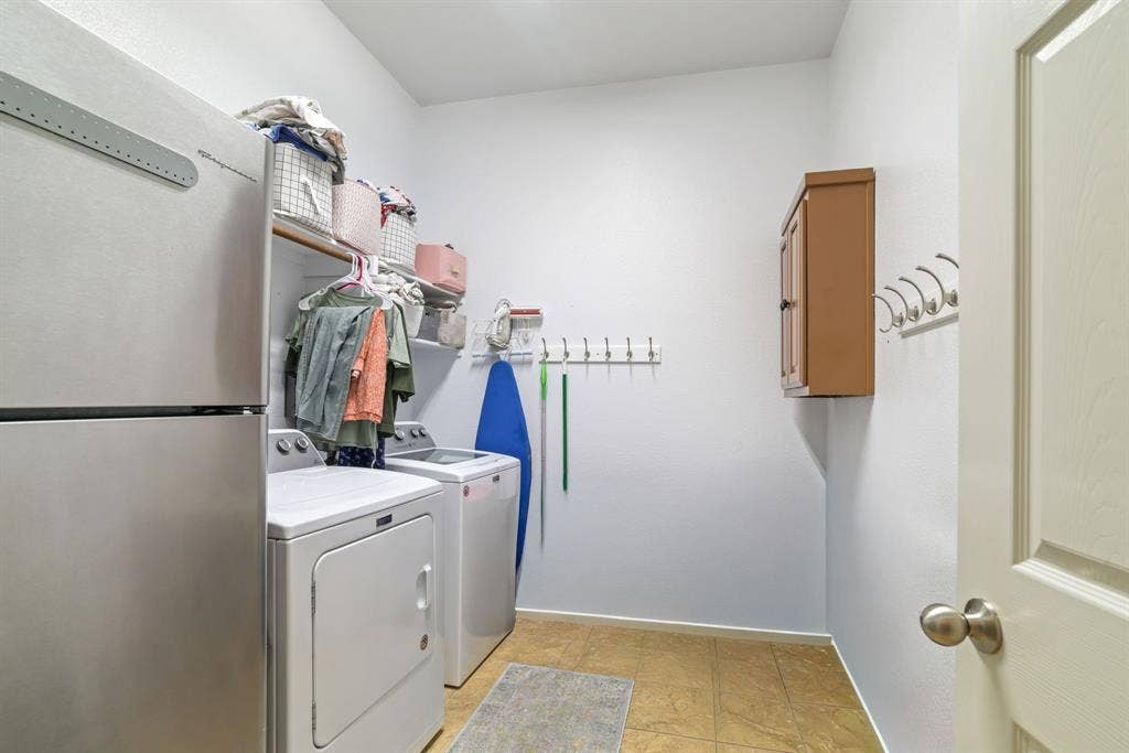 1213 Egret Court, Little Elm, TX 75068 Utility room with tile flooring, wall-mounted shelving, and a built-in wood-finish cabinet