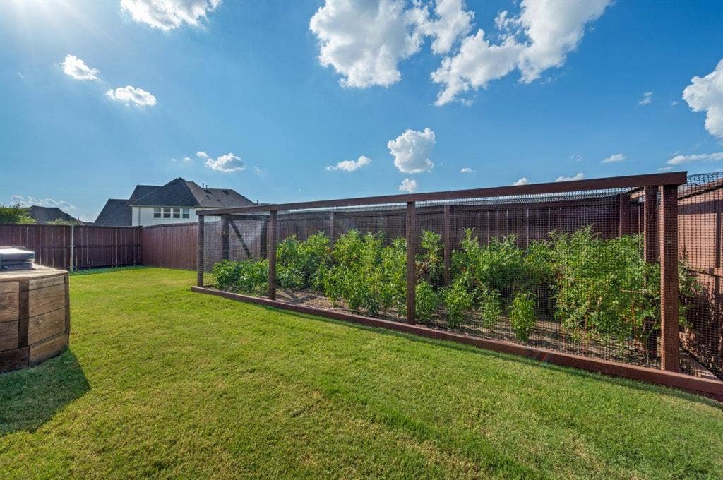 2721 Old Shire Path Road, Prosper, TX 75078 Expansive backyard featuring a lush lawn, privacy fencing, and a built-in garden enclosure