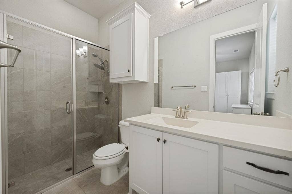 2721 Old Shire Path Road, Prosper, TX 75078 Glass-enclosed shower with a tiled surround, a built-in shelf, and a shower bench