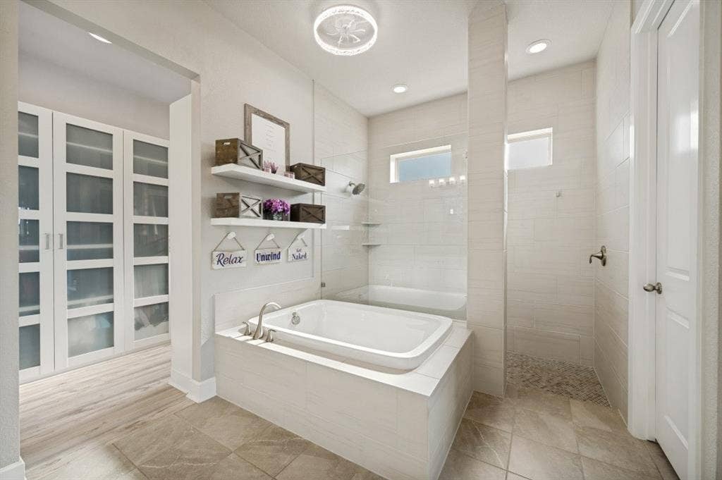 2721 Old Shire Path Road, Prosper, TX 75078 Built-in soaking tub with brushed nickel faucet, tiled shower with pebble floor, and wood-finish flooring