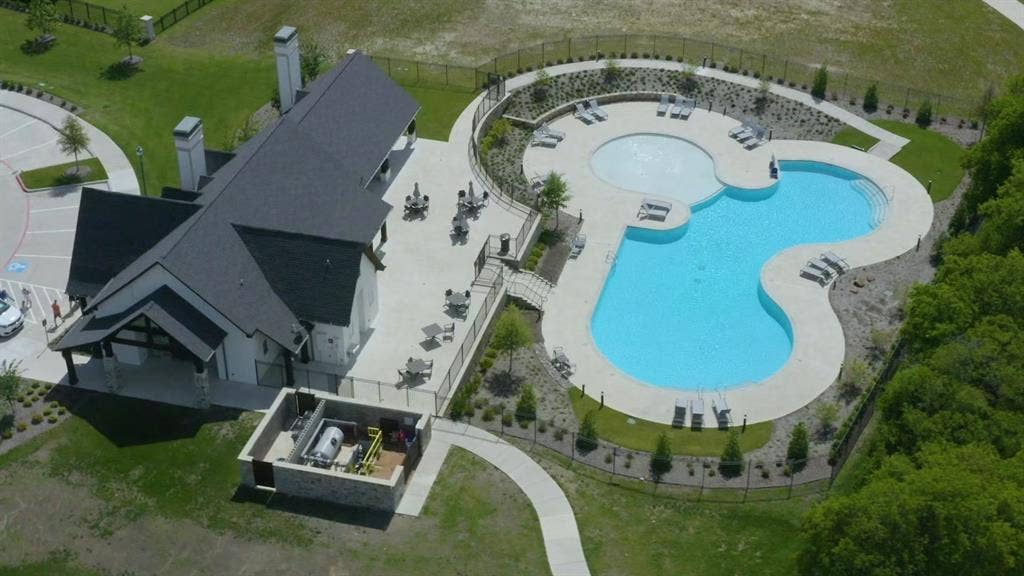 2721 Old Shire Path Road, Prosper, TX 75078 Clubhouse featuring a covered patio, adjacent swimming pool with integrated spa, and expansive paved deck area