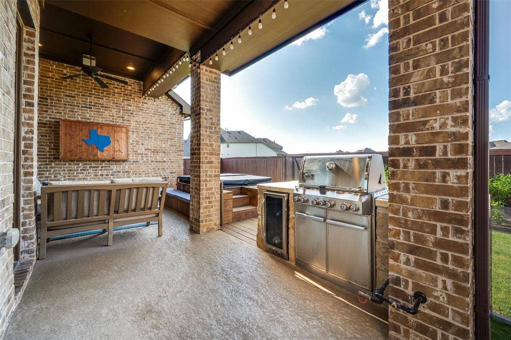 2721 Old Shire Path Road, Prosper, TX 75078 Covered patio featuring a built-in outdoor kitchen with a stainless steel grill, a compact refrigerator, a ceiling fan, and string lighting