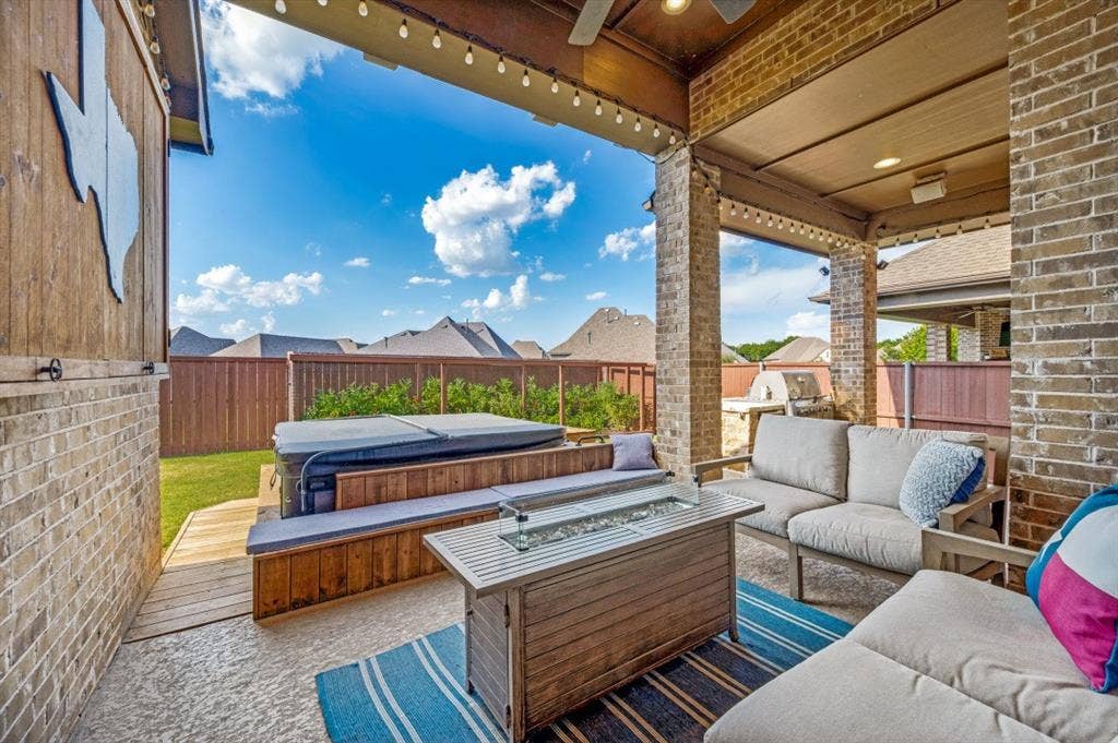 2721 Old Shire Path Road, Prosper, TX 75078 Covered outdoor patio with exposed brick columns, a built-in spa, wood-finish decking, and a privacy fence