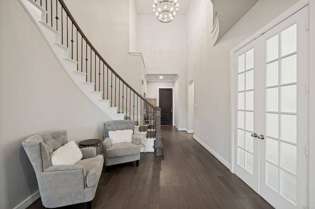 2721 Old Shire Path Road, Prosper, TX 75078 Two-story entry with curved staircase, iron balusters, wood-finish flooring, and double French doors with frosted glass