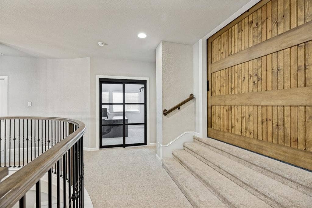 2721 Old Shire Path Road, Prosper, TX 75078 Carpeted staircase with a wood handrail, metal balusters, and a large wood barn door
