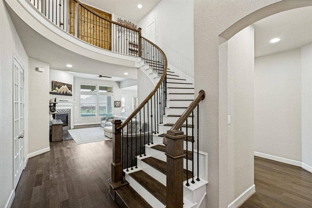 2721 Old Shire Path Road, Prosper, TX 75078 Curved staircase with wood-finish stairs and rought iron balusters