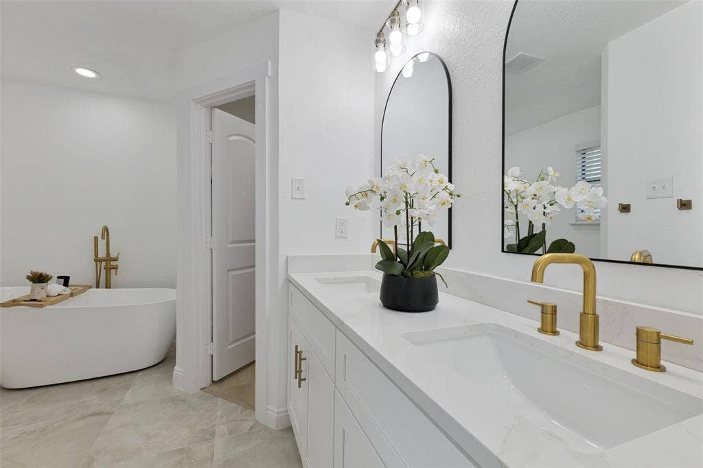 4721 Fallon Place, Dallas, TX 75227 Primary bath with a dual vanity, white shaker-style cabinetry, quartz countertop, and gold-finish fixtures