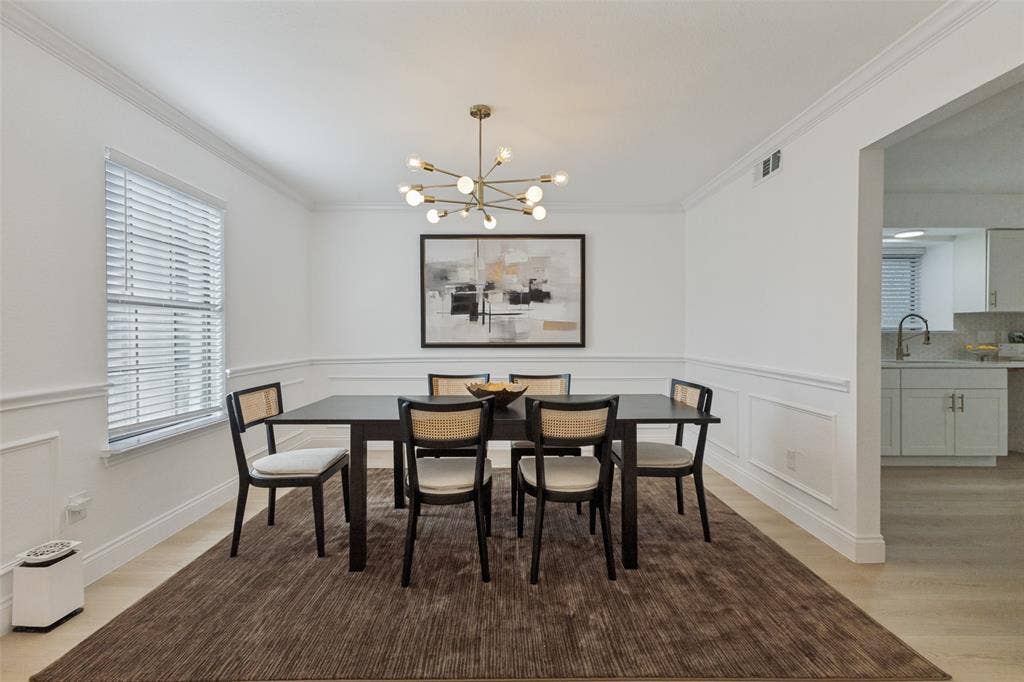 4721 Fallon Place, Dallas, TX 75227 Formal dining area featuring crown molding, wainscoting, luxury vinyl plank flooring, a contemporary chandelier, and a window with blinds