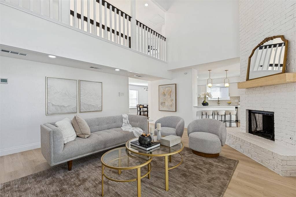 4721 Fallon Place, Dallas, TX 75227 Vaulted living room with a white brick fireplace, luxury vinyl plank flooring, and an upper-level overlook with open railing