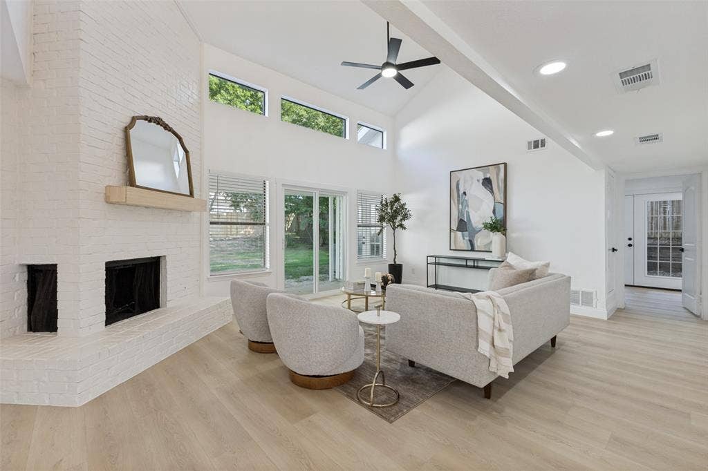 4721 Fallon Place, Dallas, TX 75227 Vaulted ceiling with an integrated ceiling fan, white brick fireplace, luxury vinyl plank flooring, transom windows, and sliding glass doors