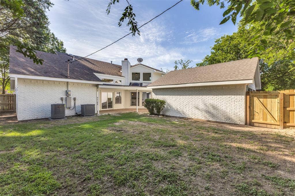 4721 Fallon Place, Dallas, TX 75227 Large fenced backyard featuring a paved patio, white brick exterior, two HVAC units, a privacy fence, and mature trees