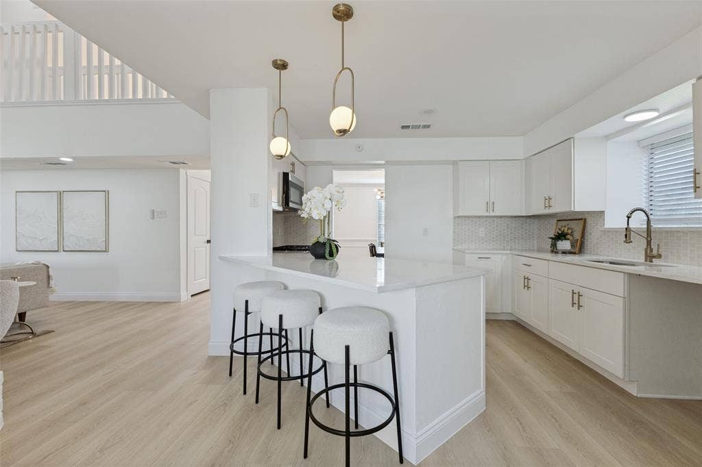 4721 Fallon Place, Dallas, TX 75227 Kitchen featuring white cabinetry, luxury vinyl plank flooring, a central island with countertop seating, stainless steel appliances, and pendant lighting