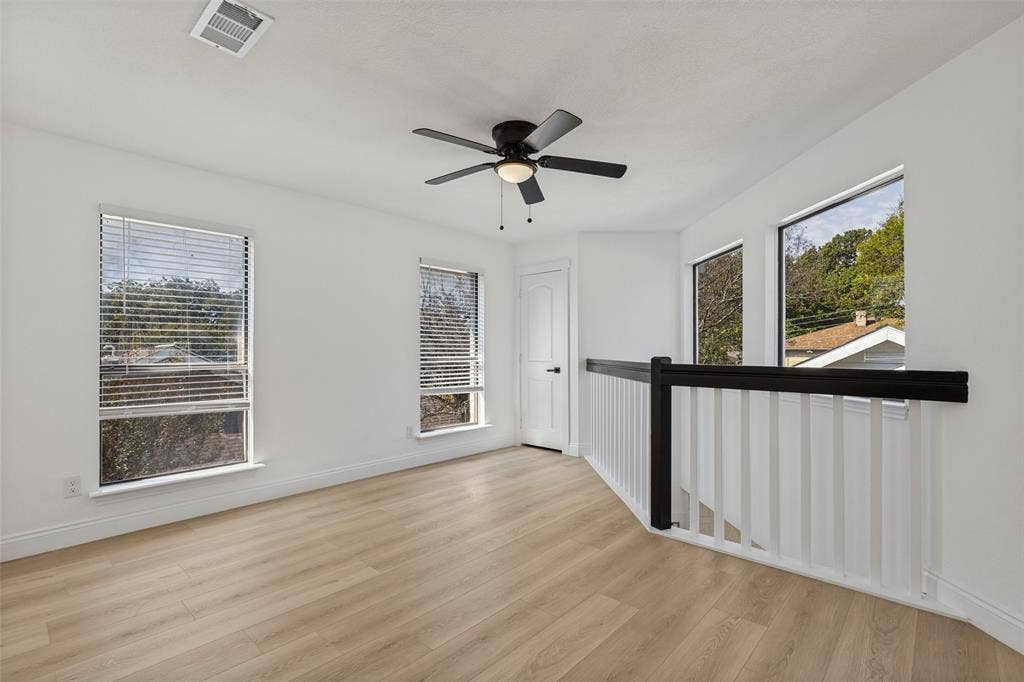 4721 Fallon Place, Dallas, TX 75227 Upstairs loft and game room with luxury vinyl plank flooring, multiple windows, a ceiling fan, and a black and white railing