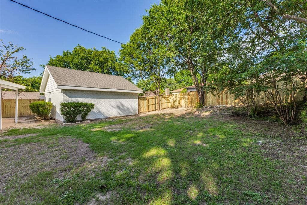 4721 Fallon Place, Dallas, TX 75227 Detached two-car garage with a gabled roof, a covered patio, and a wood privacy fence