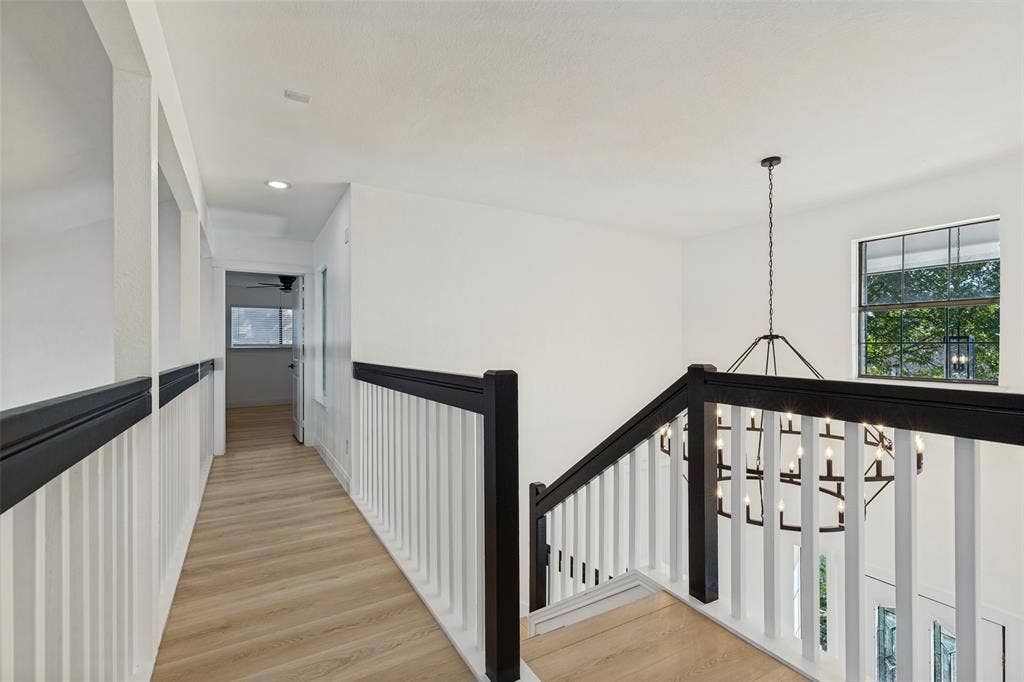 4721 Fallon Place, Dallas, TX 75227 Upstairs hallway with luxury vinyl plank flooring, white walls, and a black and white stair railing