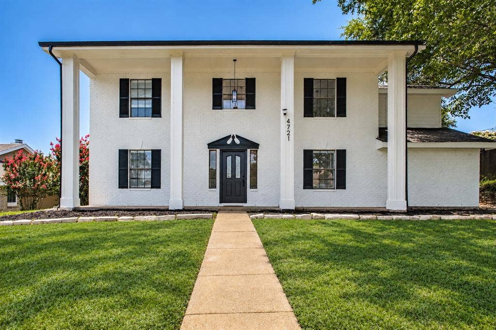 4721 Fallon Place, Dallas, TX 75227 White brick colonial exterior with prominent architectural columns, a black paneled front door, and symmetrical windows with black shutters