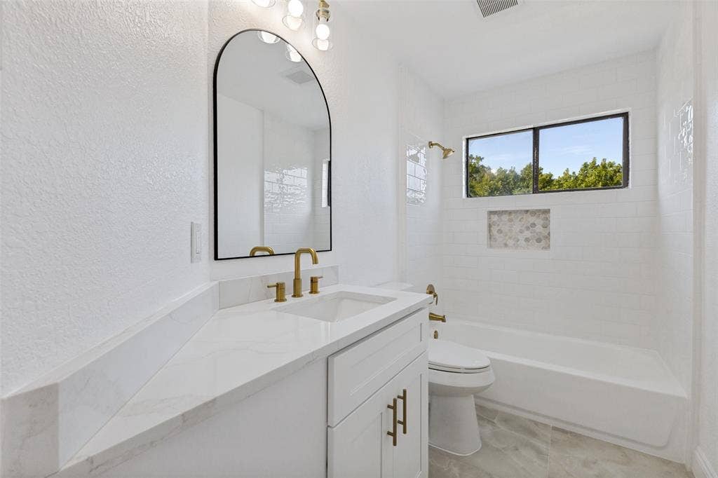4721 Fallon Place, Dallas, TX 75227 Upstairs full bath with a white vanity, quartz countertop, undermount sink, and brass-finish fixtures