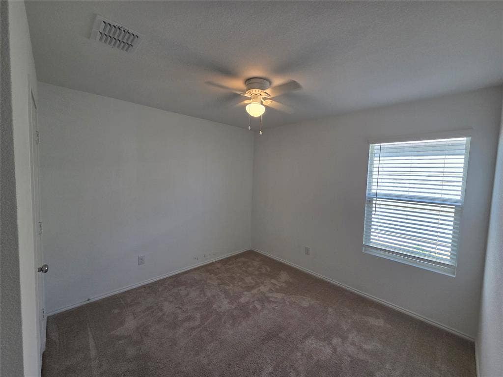 Neutral wall color, carpet flooring, window with blinds, and ceiling fan with integrated lighting