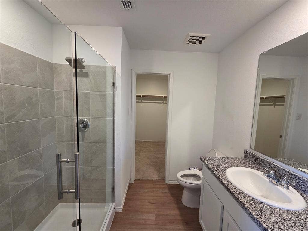 Walk-in shower with clear glass enclosure and tile surround