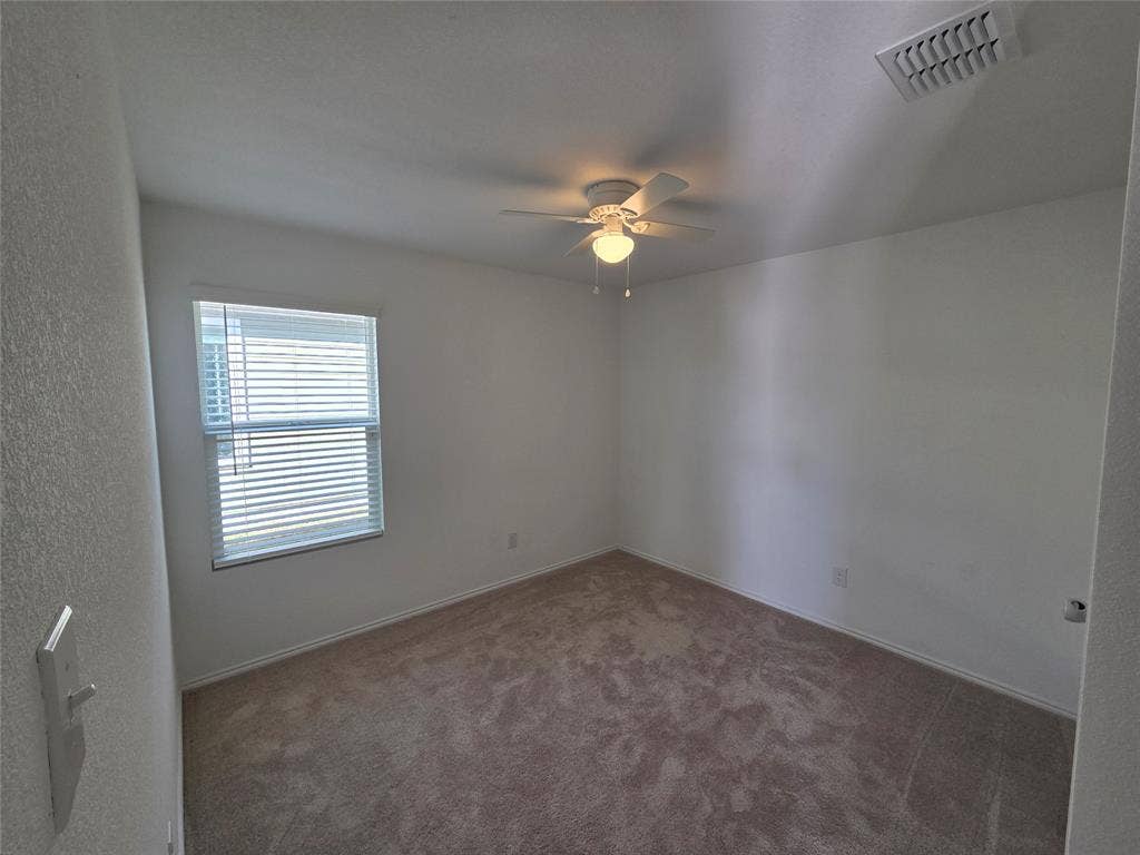 Neutral wall paint, carpeted flooring, window with blinds, and ceiling fan with integrated lighting