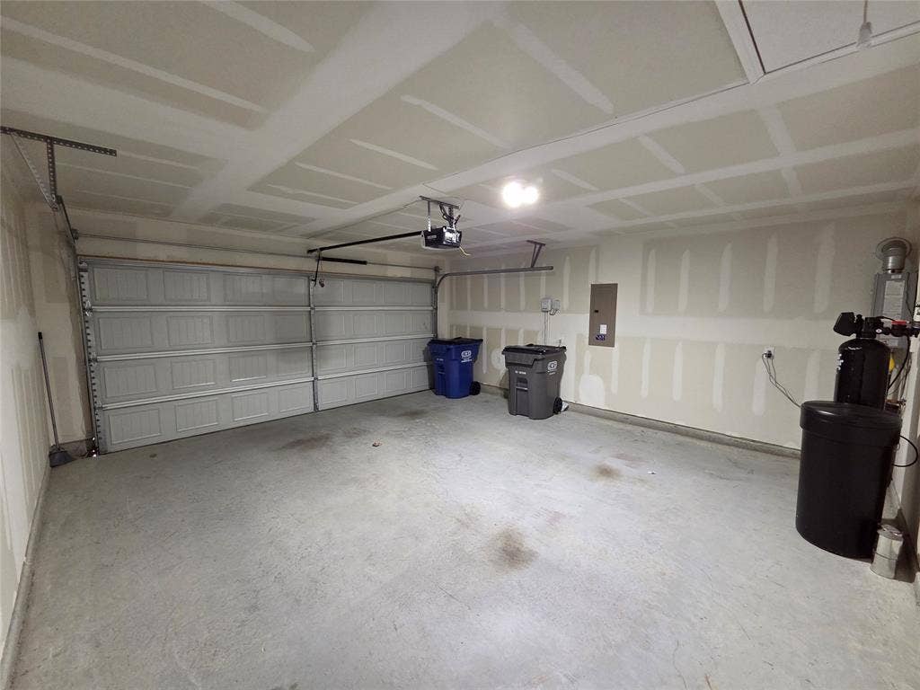 Attached garage with a panel garage door, overhead lighting, and exposed ceiling joists