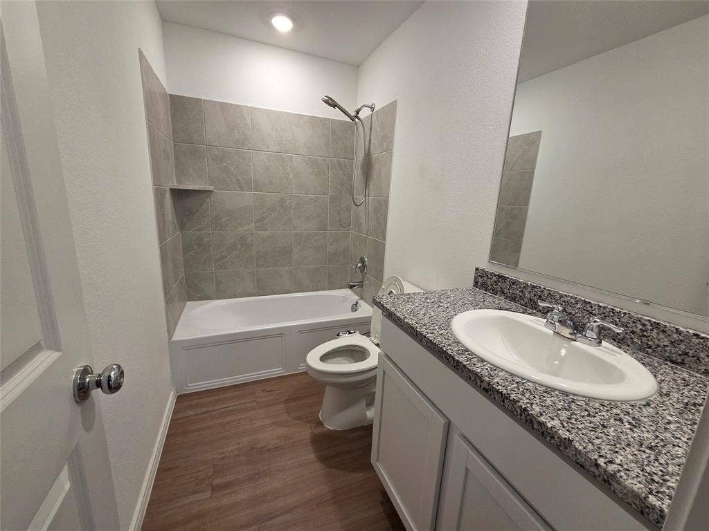 Bathroom featuring a single vanity with stone-finish countertop, undermount sink, and polished chrome faucet