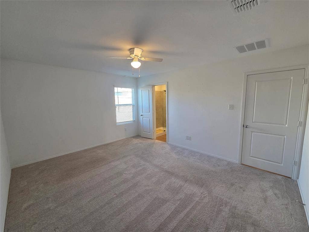 Spacious room with plush carpet, a ceiling fan, and a window with blinds
