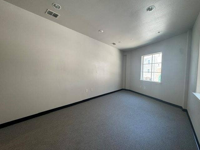 Recessed lighting, light gray wall finish, dark gray carpet, white window trim, and black baseboards