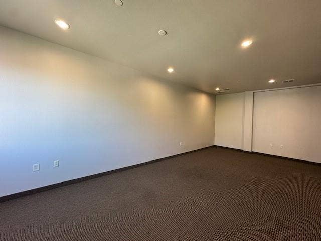 Recessed lighting illuminates the neutral-toned walls and textured carpeting