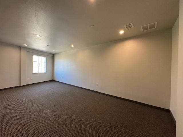Expansive room featuring recessed lighting, a window with grid detailing, and patterned carpet flooring
