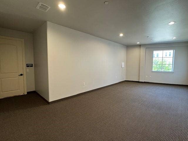 Recessed lighting, large window with natural light, textured carpet flooring, and a neutral color palette