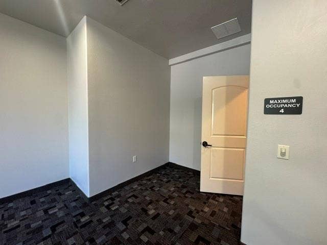6675 Mediterranean Drive, #202, McKinney, TX 75072 Wall-to-wall patterned carpet flooring, neutral painted walls, and a white interior door with a black handle