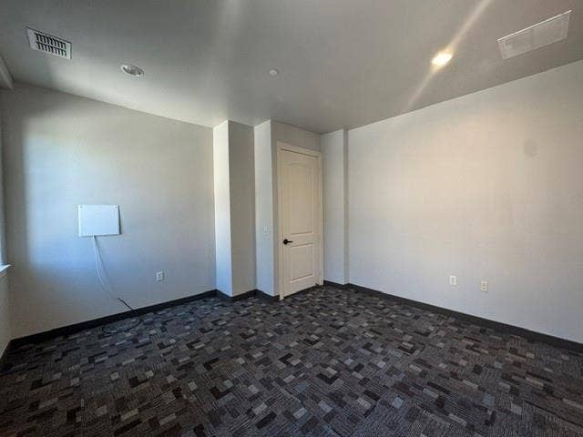 Recessed ceiling lighting, patterned carpet flooring, white interior door, and light-colored walls