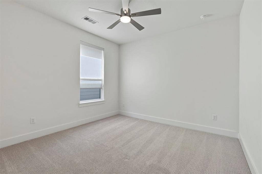 This room serves as a bright and spacious secondary bedroom, featuring ample natural light and neutral finishes that make it a versatile space for guests or family members.