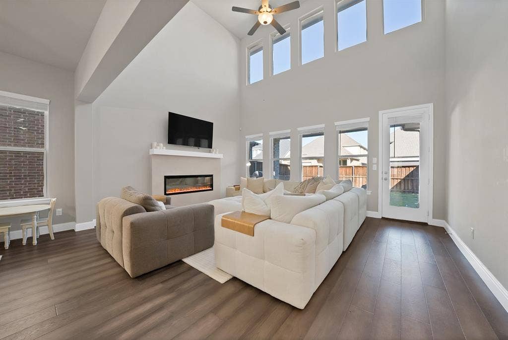 1837 Averi Lane, Farmers Branch, TX 75234 Soaring ceilings, wood-finish flooring, an electric fireplace, multiple windows, and a ceiling fan