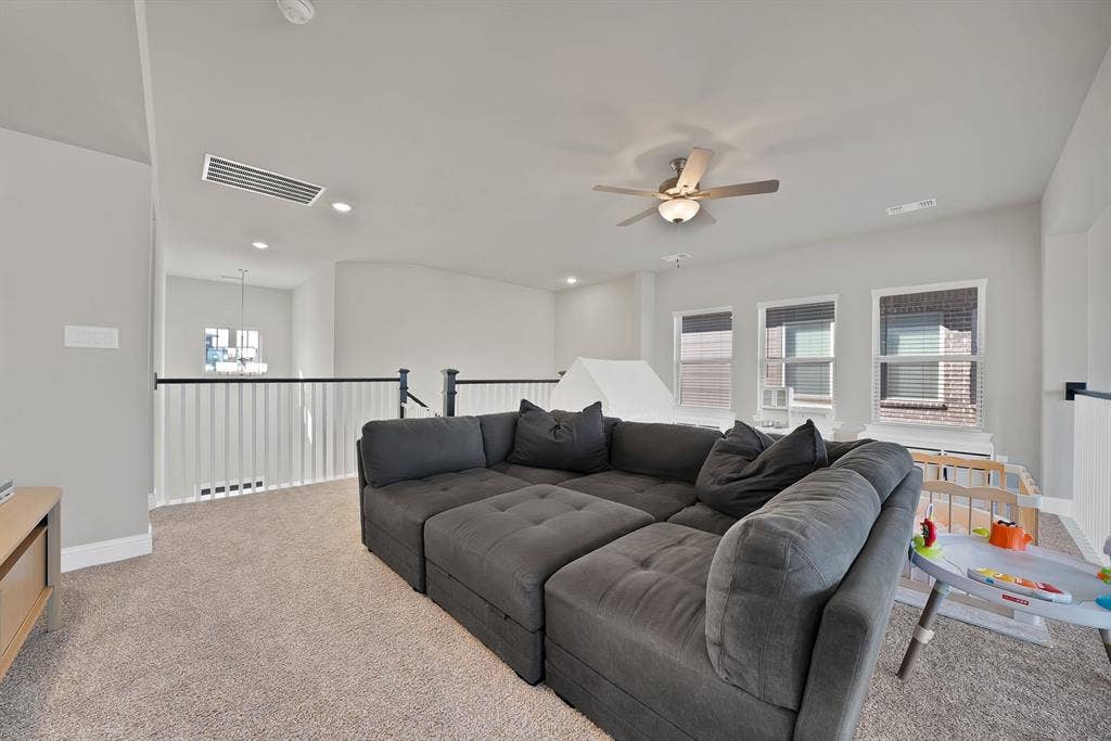 1837 Averi Lane, Farmers Branch, TX 75234 Carpeted loft space featuring a ceiling fan, three windows, and a white baluster railing with a black handrail