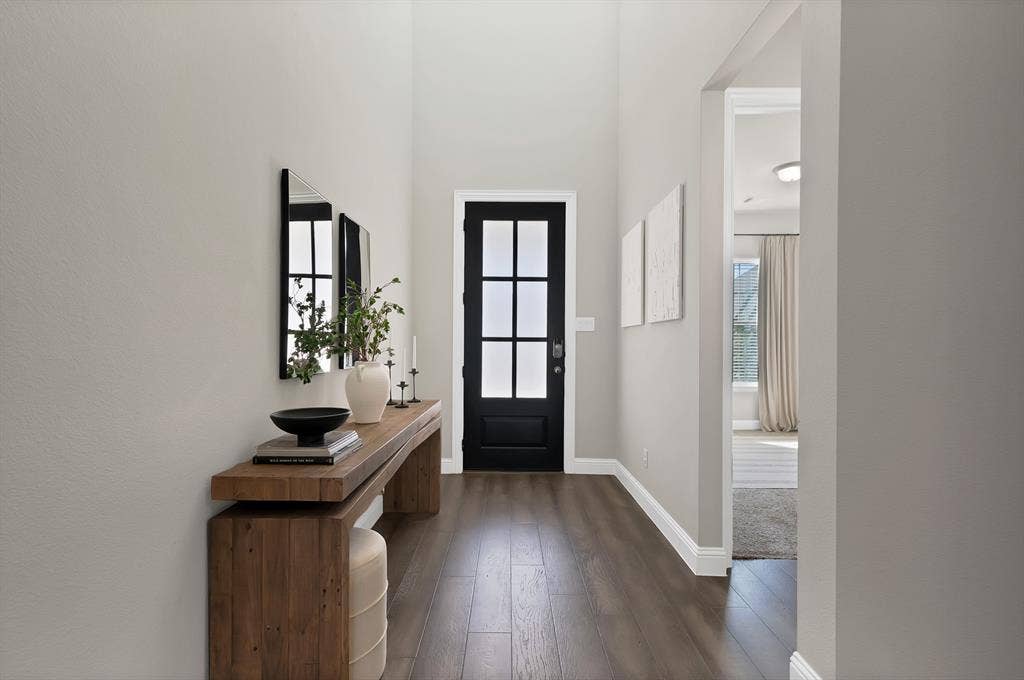 1837 Averi Lane, Farmers Branch, TX 75234 Wood-finish flooring with crisp white trim, a black paneled door, and neutral wall tones