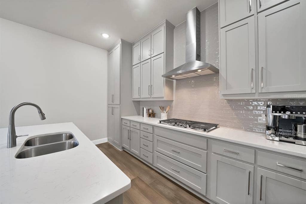 1837 Averi Lane, Farmers Branch, TX 75234 Gray shaker cabinetry, undermount double-basin sink, stainless steel range hood, stone-finish countertops, and wood-finish flooring