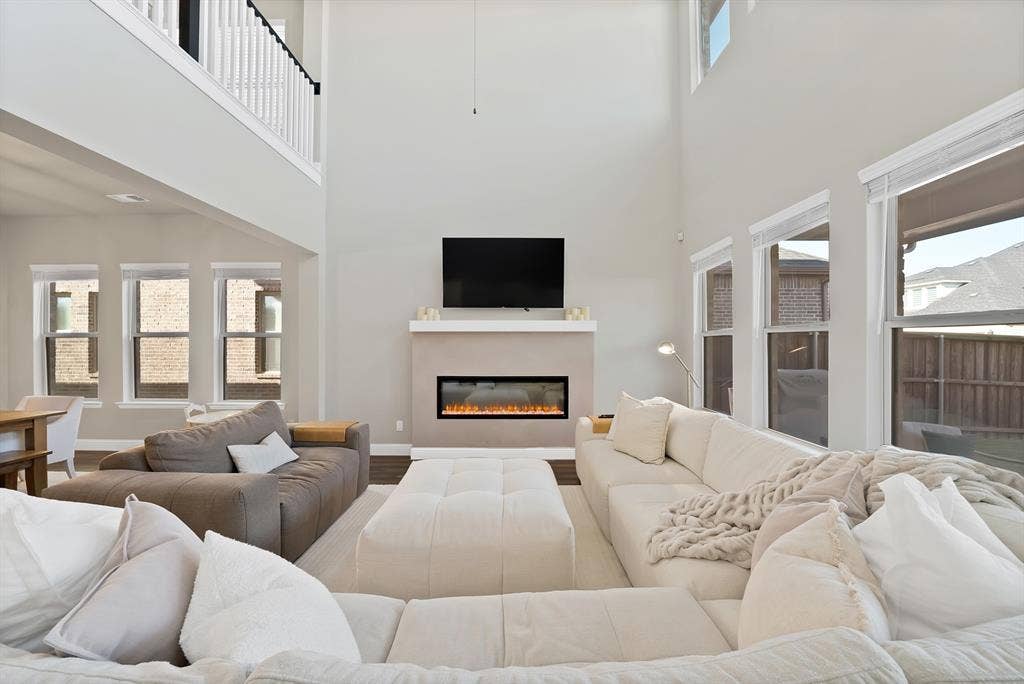 1837 Averi Lane, Farmers Branch, TX 75234 Two-story living area with high ceilings, multiple windows, built-in fireplace, and upper-level railing