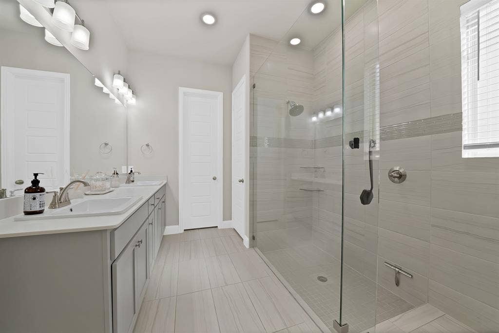 1837 Averi Lane, Farmers Branch, TX 75234 Dual vanity with undermount sinks, a spacious walk-in shower with a glass enclosure, light-toned tile flooring, and recessed lighting